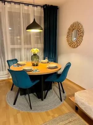 a dining room table with blue chairs and aendant light at Family Arena Prague in Prague