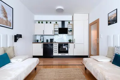 a living room with two couches and a kitchen at Family Arena Prague in Prague
