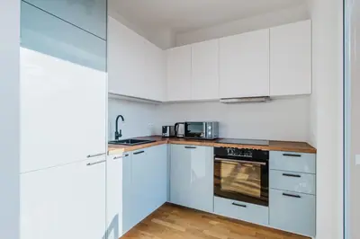 a white kitchen with white cabinets and a stove at Blueground Žižkov furnished park PRG-42 in Prague