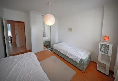 a white bedroom with two beds and a lamp at Pleasant apartment close to city center in Prague