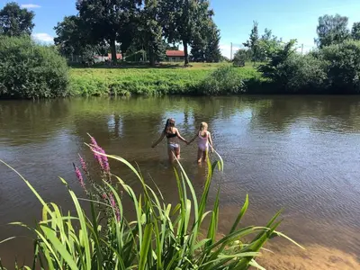 two girls walking in the water in a river at Cottage by the Jizera river in Nový Vestec