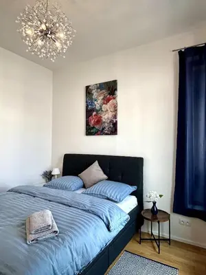 a bedroom with a blue bed and a chandelier at Viktoria Suite N6 with Garage & Balcony in Prague