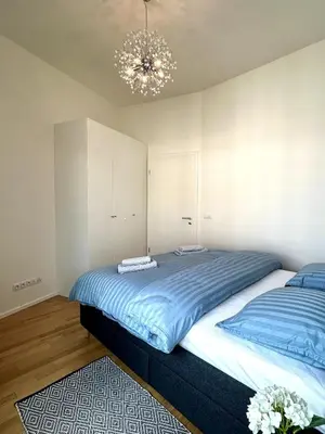 a bedroom with two beds and a chandelier at Viktoria Suite N6 with Garage & Balcony in Prague