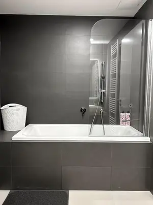 a bath tub in a bathroom with black walls at Viktoria Suite N6 with Garage & Balcony in Prague