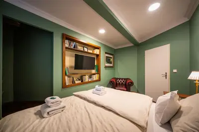 a bedroom with green walls and two beds with towels at PilotsApartments in Prague