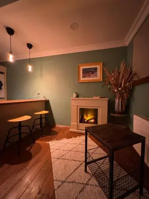 a living room with a fireplace and a table and stools at PilotsApartments in Prague
