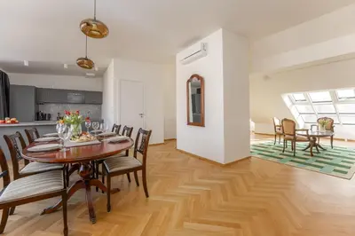 a white bedroom with a bed and a wooden floor at Visit Oomph Apartments in Prague
