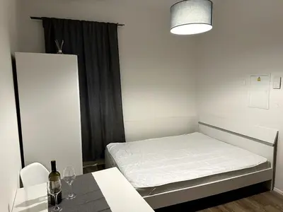 a small white room with a bed and a table at Florenc Apartment in Prague