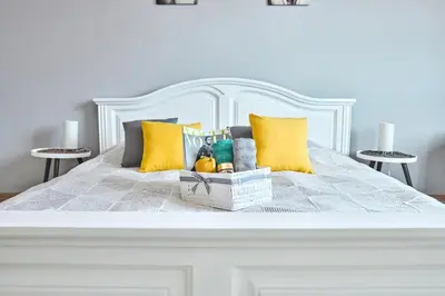 a white bed with yellow pillows and a basket on it at SOEL apartments in Prague