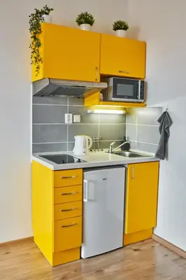 a small kitchen with yellow cabinets and a sink at SOEL apartments in Prague
