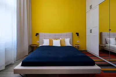 a bedroom with a large bed with a yellow wall at Spectrum Apartment in Prague