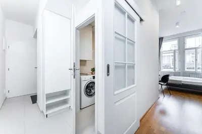 a white hallway with a door and a washing machine at Rentero Charles square studio apartment Parking on request in Prague