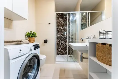 a white washer and dryer in a bathroom with a sink at Rentero Charles square studio apartment Parking on request in Prague
