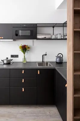 a kitchen with black cabinets and a sink at Urban Wave Apartment in Prague