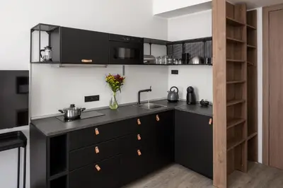 a kitchen with black cabinets and a sink at Urban Wave Apartment in Prague