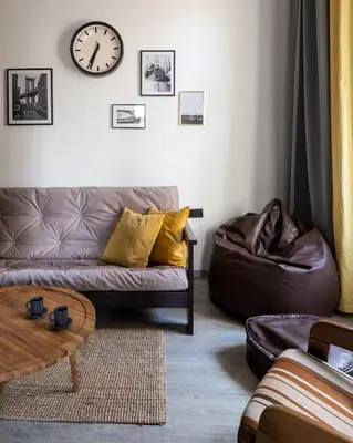 a living room with a couch and a clock on the wall at Urban Wave Apartment in Prague