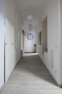 an empty hallway with white walls and a clock on the wall at Urban Wave Apartment in Prague