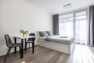 a white bedroom with a bed and a table and chairs at 12 min Centrum, 200Mb WIFI, Onsite Supermarket in Prague