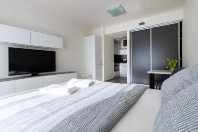 a white bedroom with a large bed and a flat screen tv at 12 min Centrum, 200Mb WIFI, Onsite Supermarket in Prague