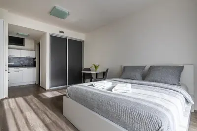 a white bedroom with a large bed and a table at 12 min Centrum, 200Mb WIFI, Onsite Supermarket in Prague