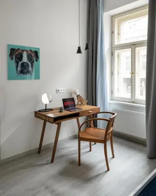 a desk and a chair in a room with a dog painting at Ocean Breeze Apartment in Prague