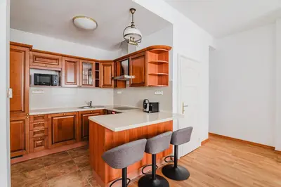 a kitchen with wooden cabinets and a counter with two stools at Blueground Prague 1 furnished Old town square PRG-43 in Prague