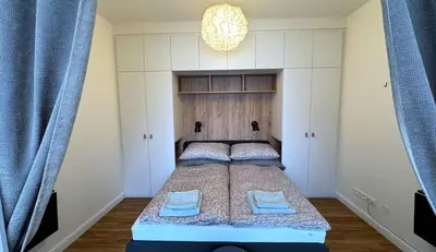 a bedroom with a bed with blue curtains and a chandelier at Short Way Apartments in Prague