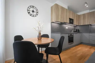 a kitchen with a table and chairs and a clock at Viktoria Suite N3 with Garage & Balcony in Prague
