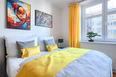a bedroom with a bed with yellow pillows and a window at Apartmán Flora in Prague