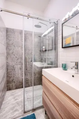 a bathroom with a glass shower and a sink at Apartmán Flora in Prague