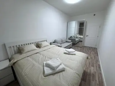 a white bedroom with a large bed with towels on it at Modern, comfortable apartments near the metro in Prague