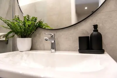 a bathroom sink with a black soap dispenser on it at Sunny & Quiet studio in peaceful hood,metro access in Prague