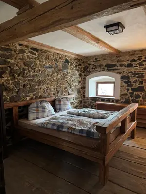 a bedroom with a bed in a stone wall at Ekologická farma Skřivaň in Skřivaň