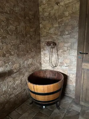 a wooden tub in a bathroom with a stone wall at Ekologická farma Skřivaň in Skřivaň