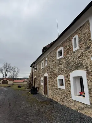 an old stone building with white windows and a driveway at Ekologická farma Skřivaň in Skřivaň