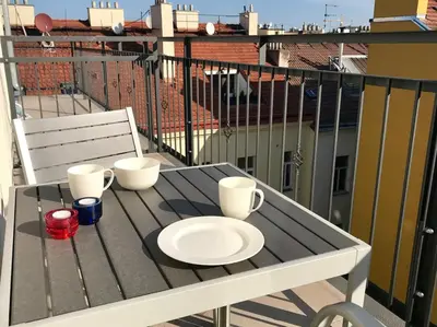 a table with a plate and cups on a balcony at Apartment with a terrace and AC in the city center in Prague