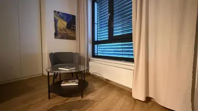a room with a chair and a table and a window at NEW STYLISH APARTMENT Varta Alpha 2025 & Parking in Prague