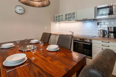 a kitchen with a wooden table with plates and wine glasses at 1 Bed Flat - Sleeps 5 - Parking - Wifi in Prague