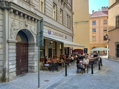 a group of people sitting at tables outside a building at Luxury Design Apartment at Old Town Square with Air Condition in Prague