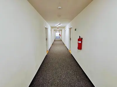a corridor of an empty hallway with a fire extinguisher at TERRACE-VIEW PRAGUE APARTMENTS for Business & Leisure, FREE PARKING & Gym, Near Metro & Aqua Sport Centre in Prague