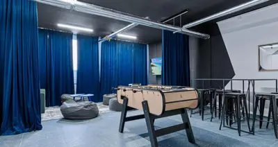 a ping pong table in a room with blue curtains at LIVE-INN PRAGUE SUPERIOR SUITE FOR 1-4 GUESTS, 20 Mins to center, Lift, Gym, Reception, Parking, Roof Terrace, Game & Party Room in Prague