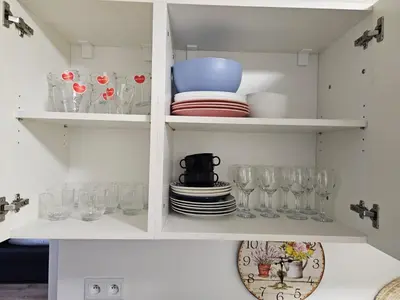 a white cabinet filled with glasses and plates at LIVE-INN PRAGUE SUPERIOR SUITE FOR 1-4 GUESTS, 20 Mins to center, Lift, Gym, Reception, Parking, Roof Terrace, Game & Party Room in Prague