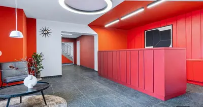 an office lobby with red walls and a table at LIVE-INN PRAGUE SUPERIOR SUITE FOR 1-4 GUESTS, 20 Mins to center, Lift, Gym, Reception, Parking, Roof Terrace, Game & Party Room in Prague