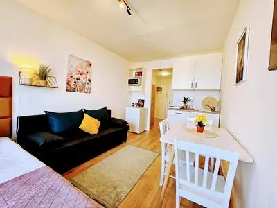 a living room with a black couch and a table at LIVE-INN PRAGUE SUPERIOR SUITE FOR 1-4 GUESTS, 20 Mins to center, Lift, Gym, Reception, Parking, Roof Terrace, Game & Party Room in Prague