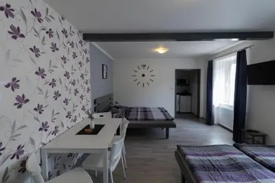 a living room with a table and a clock on the wall at Apartmány Kamejk in Kamýk nad Vltavou