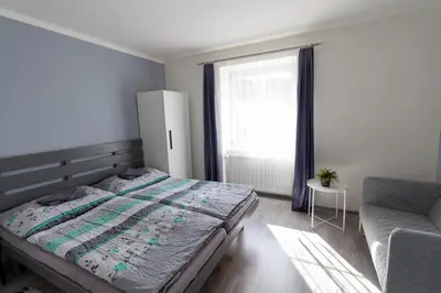a bedroom with a bed and a chair and a window at Apartmány Kamejk in Kamýk nad Vltavou
