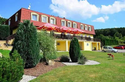 a building with umbrellas and trees in front of it at Apartmány Kamejk in Kamýk nad Vltavou
