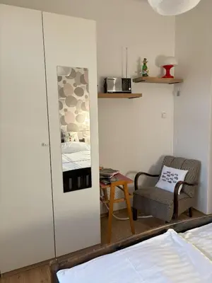 a bedroom with a bed and a chair and a mirror at Vintage Brussels Style on Prague 4 in Prague