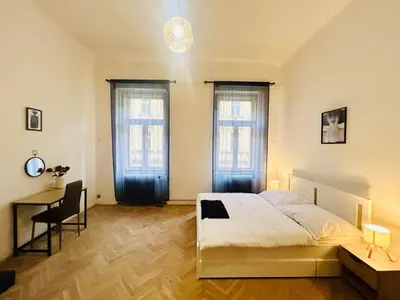 a bedroom with a bed and a desk and two windows at Retro style in centrum Prague Andel in Prague