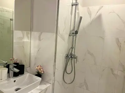 a white bathroom with a shower and a sink at Spacious 4BR Apartment by Charles Bridge in Prague